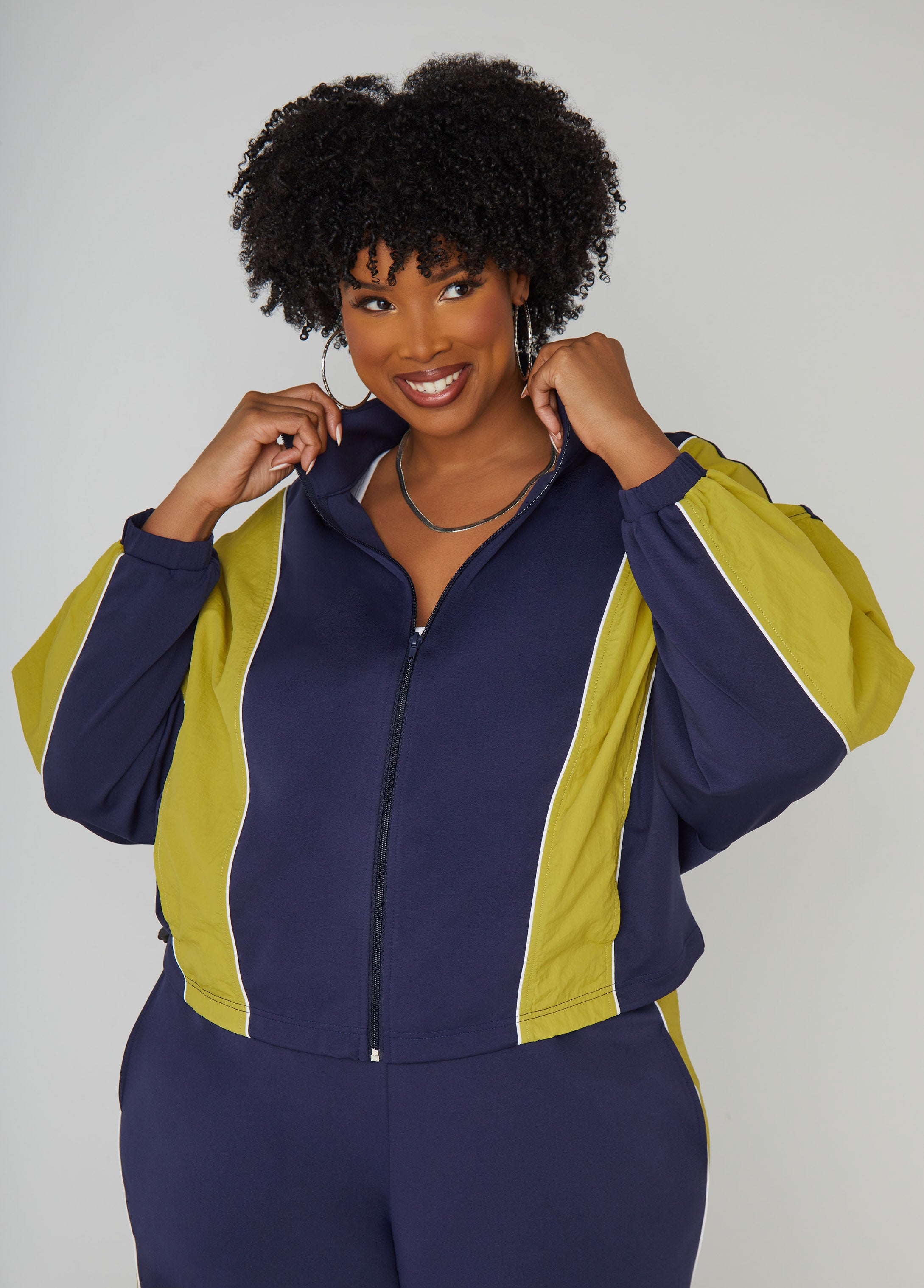 Two-tone stretch-knit track jacket with two slit pockets at sides, woven panels, piped trims and elasticized sleeve cuffs. Zip fastening through front. Length: 25in. Can be worn as a two-piece set with matching pants. Pants sold separately.